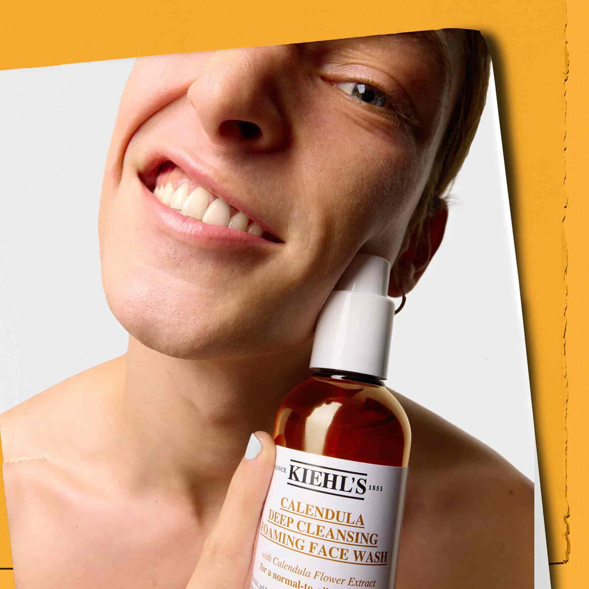 Model drži bočicu Kiehl's Calendula Deep Cleaning Foaming Face Wash gela za čišćenje lica