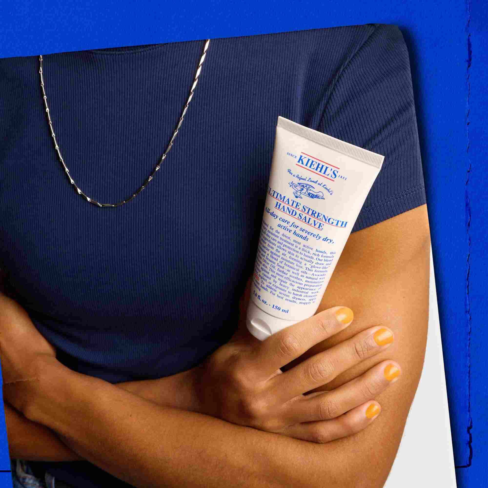 Model drži tubu Kiehl's Ultimate Strength Hand Salve