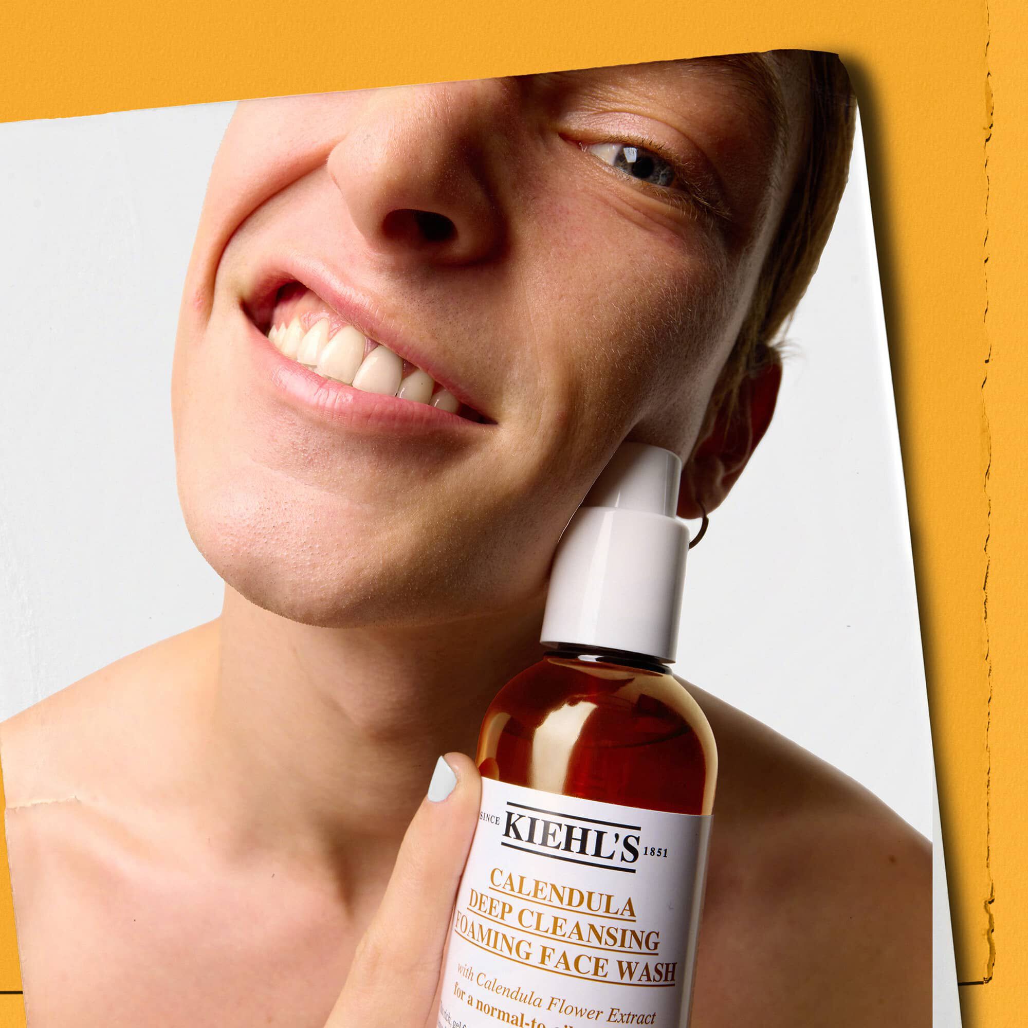 Model drži bočicu Kiehl's Calendula Deep Cleaning Foaming Face Wash gela za čišćenje lica