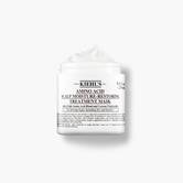 A graphic featuring an open white jar of Kiehl's Amino Acid Scalp Moisture-Restoring Treatment Mask, with a visible white creamy product inside.
