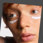Krupni plan kože koji prikazuje nanošenje kreme Kiehl's Age Defender Eye Repair.