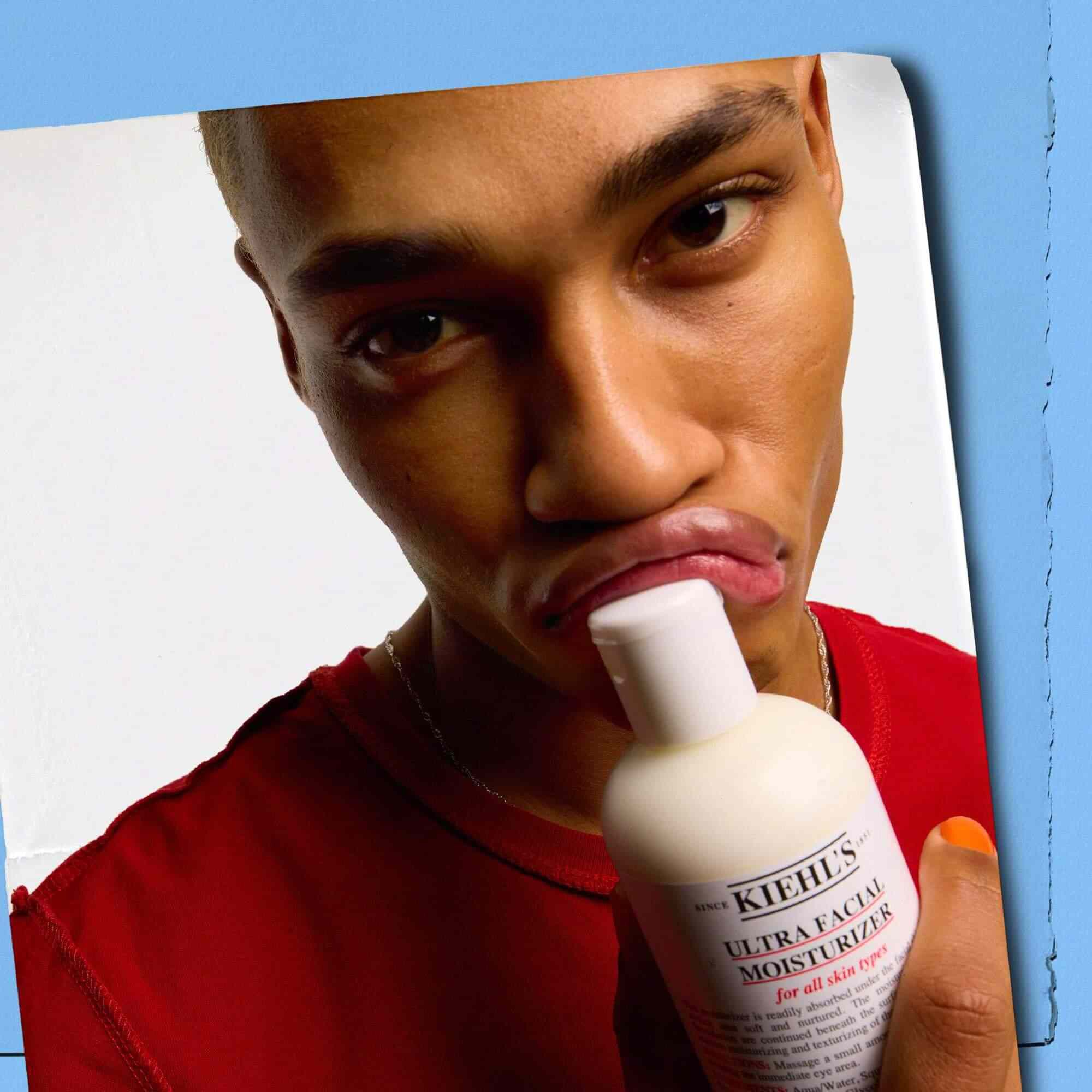 Model pritiska bočicu Kiehl's Ultra Facial Moisturizer uz usne