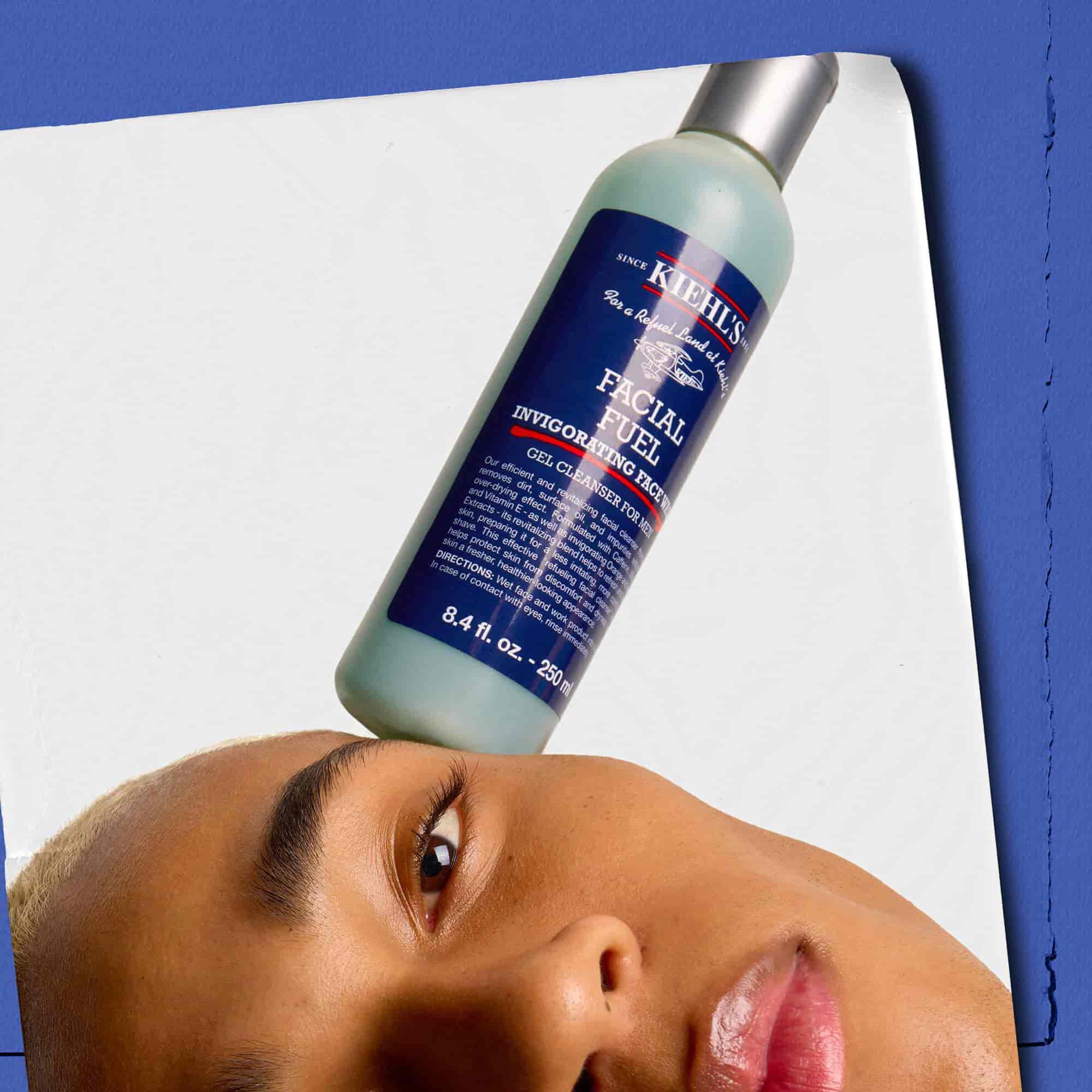 Model sa bočicom energizirajućeg gela za pranje lica Kiehl's Facial Fuel na licu