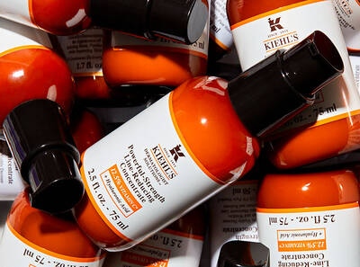 A variety of Kiehl's Powerful-Strength Line-Reducing Concentrate bottles piled together, showcasing their vibrant orange packaging.