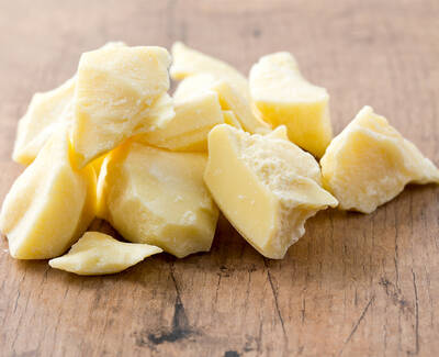 Chunks of yellow shea butter scattered on a wooden surface.
