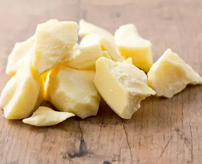 Chunks of yellow shea butter scattered on a wooden surface.