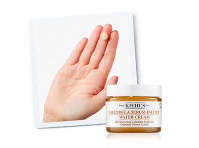 Krema sa ekstraktom nevena u posudi, raširena na dlanu za demonstraciju teksture.