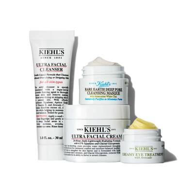 A collection of Kiehl's skincare products, including a facial cleanser, cleansing masque, facial cream, and an eye treatment, all displayed in jars and tubes of varying sizes.