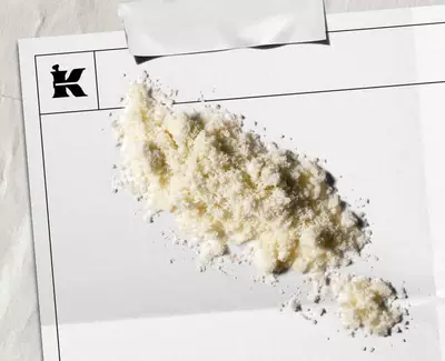Prljavo beli prah koji predstavlja 1% koloidne zobene pahuljice na belom listu sa crnim Kiehl's logotipom u uglu.