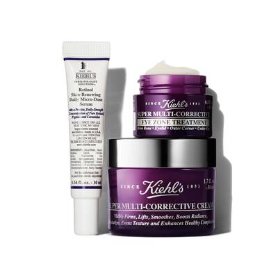 A flat lay of three Kiehl's skincare products: a tube of Retinol Skin-Renewing Daily Micro-Dose Serum and two jars of Super Multi-Corrective Eye Zone Treatment and Super Multi-Corrective Cream, all with purple packaging.