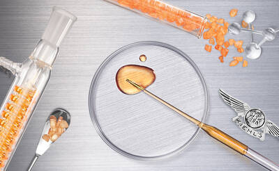 A flat lay image featuring glass laboratory equipment, including a test tube and petri dish containing a golden liquid, alongside a metal spoon with orange crystals, all arranged on a brushed metal background. The Kiehl's logo is visible.