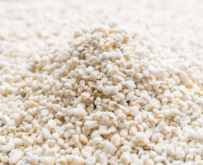 A close-up of a mound of small, white pebbles or granules, creating a textured surface.