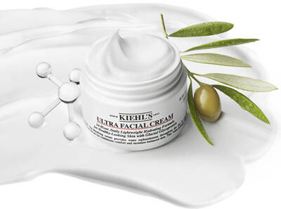 A jar of Kiehl's Ultra Facial Cream surrounded by a smooth white cream and an olive branch.